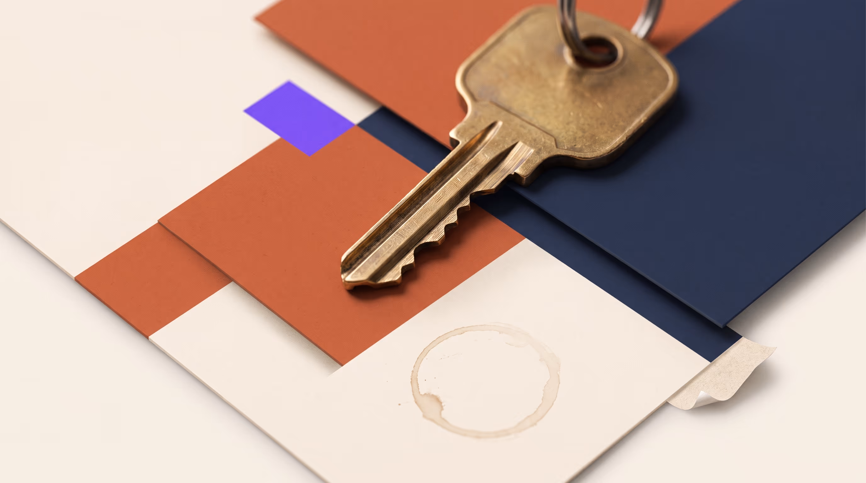 Worn brass key resting across layered cream, terracotta and indigo panels with a coffee ring and a peeling paper corner